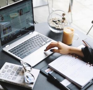 Digital marketer working on a laptop at a modern office desk with coffee, notebook, and workspace essentials for online marketing and productivity.